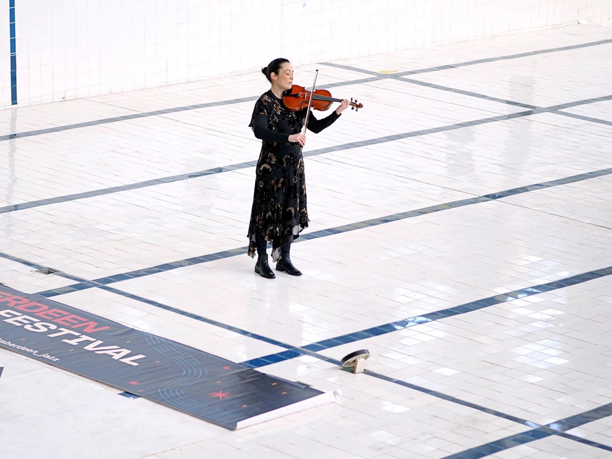woman playing violin in a swiiming pool emptied of water