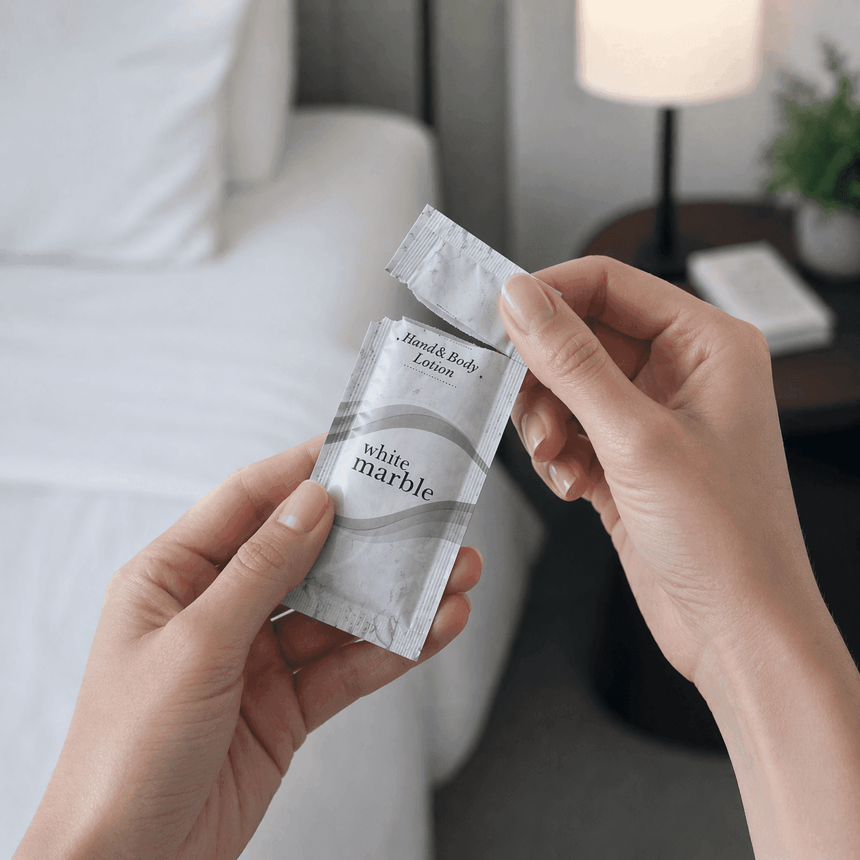 Breck® Hair & Body Care sachet being opened by a woman with natural nails in a softly lit hotel room setting