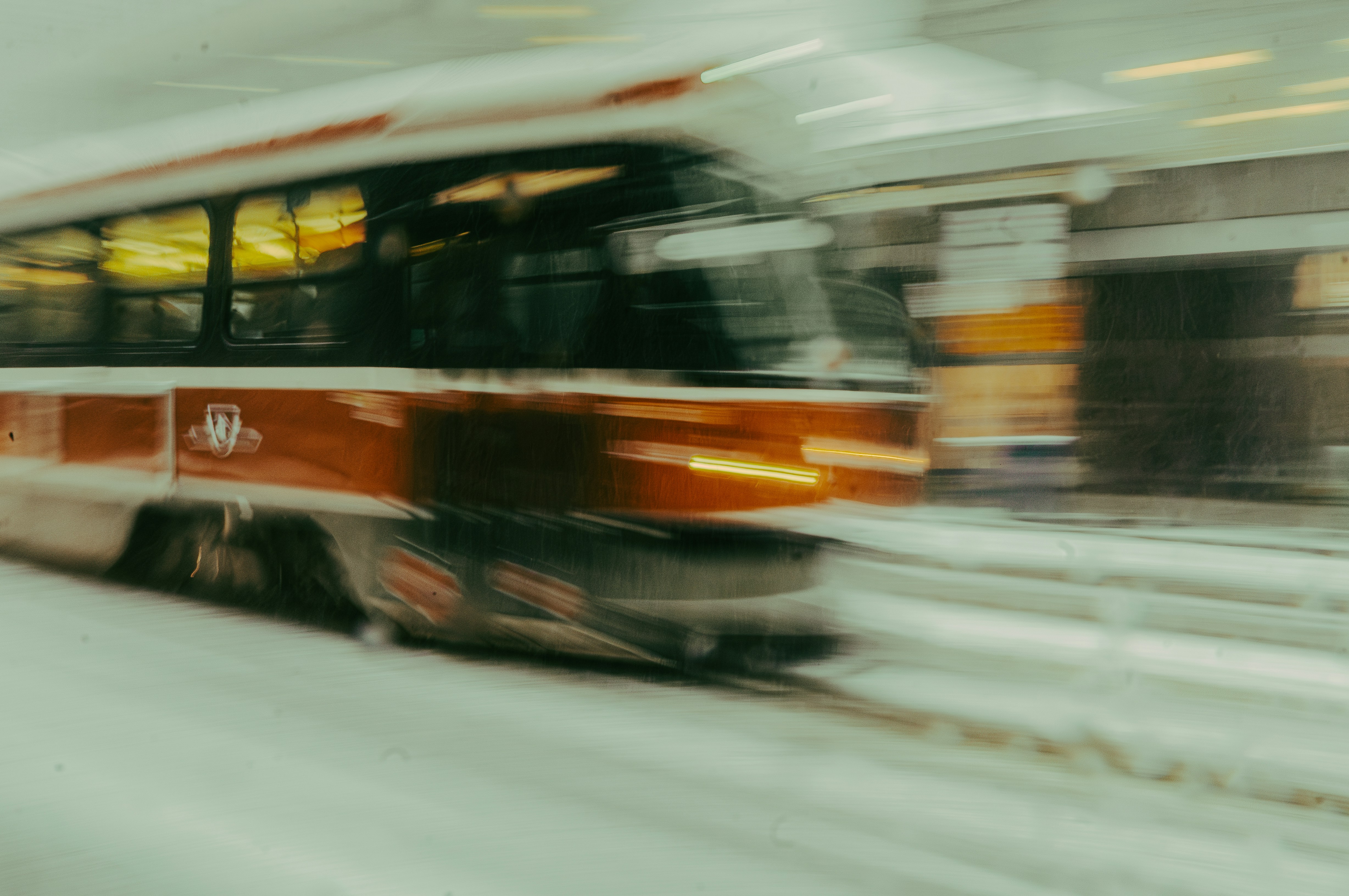 A red and white bus driving down a snow covered street