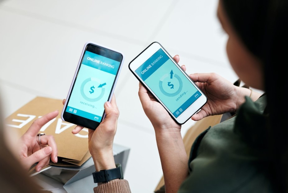 Two women holding phones and transferring money. 