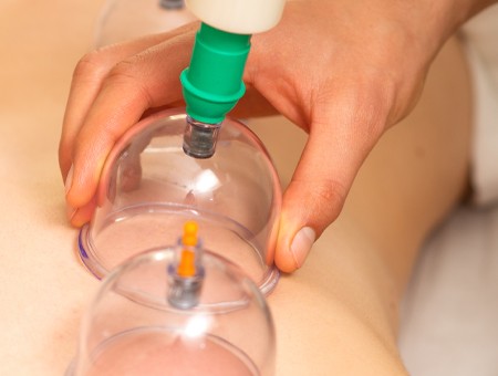 A person with curly hair sits at a desk, working on a laptop in a cozy, well-lit environment.