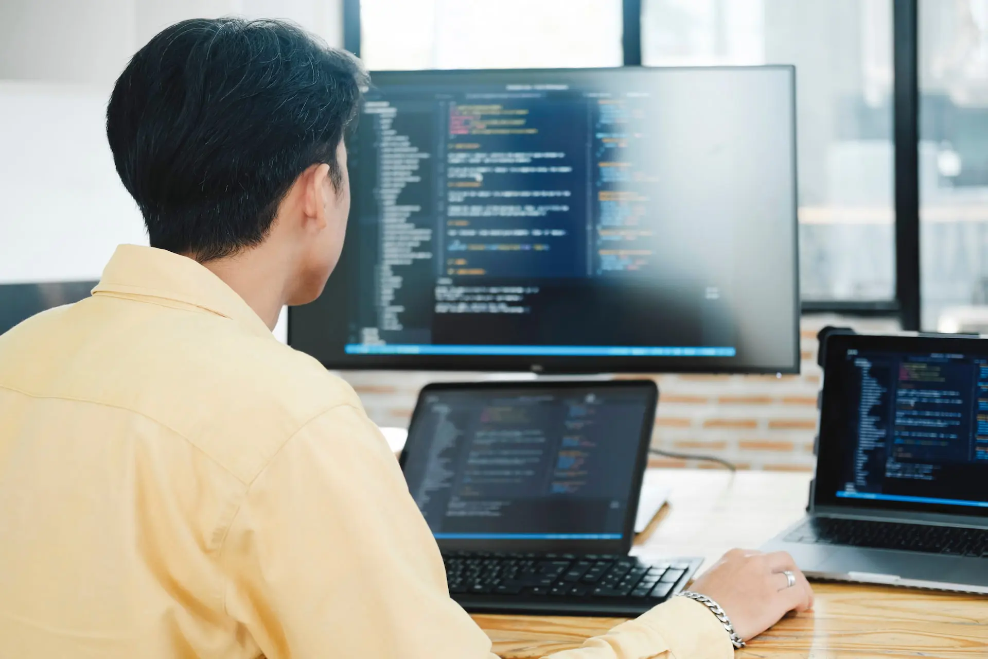 Programmeur werkt aan computerscherm met code in een modern kantoor.