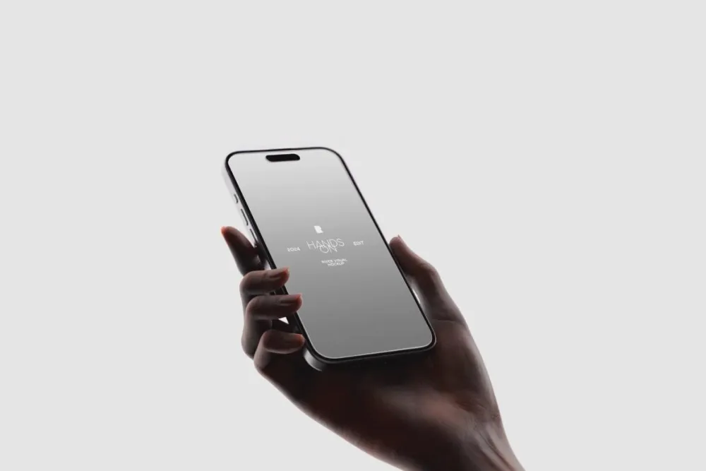 A minimalist iPhone mockup held in a hand against a light gray background, emphasizing the phone's sleek design and reflective screen in soft, natural lighting.