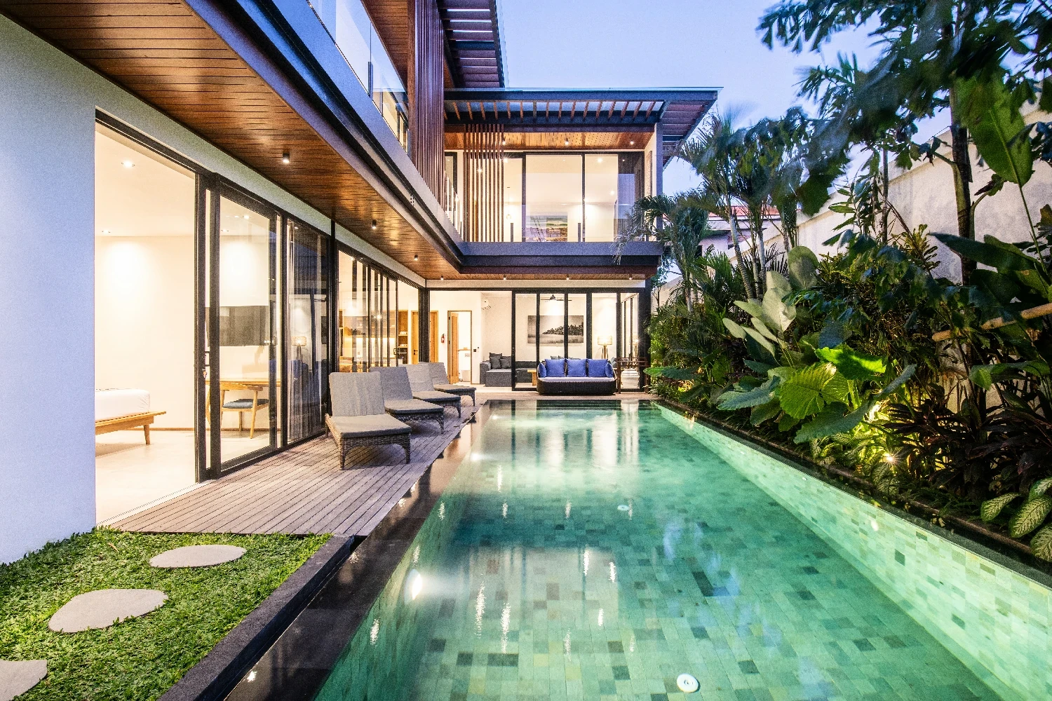Evening view of a lit swimming pool at a contemporary Canggu villa, perfect for real estate investment.