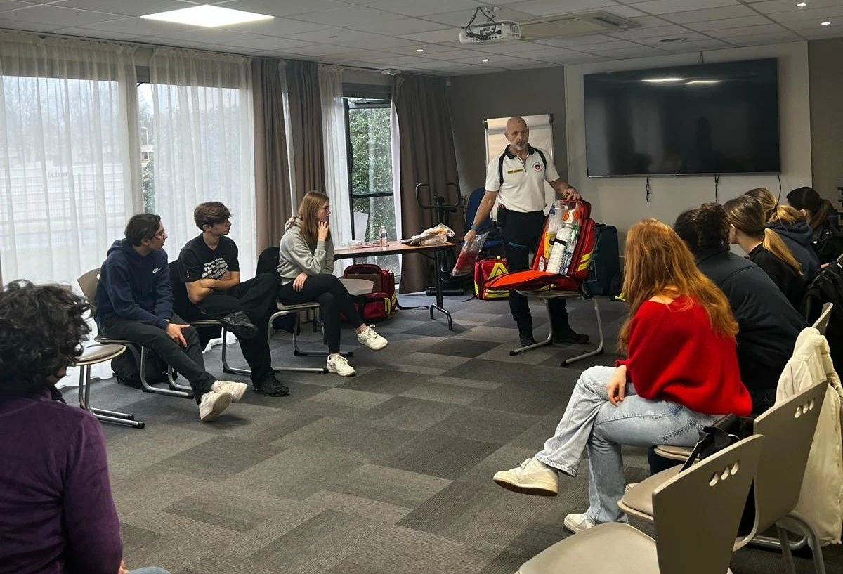 Formation aux premiers secours avec un instructeur et groupe attentif dans une salle de conférence.