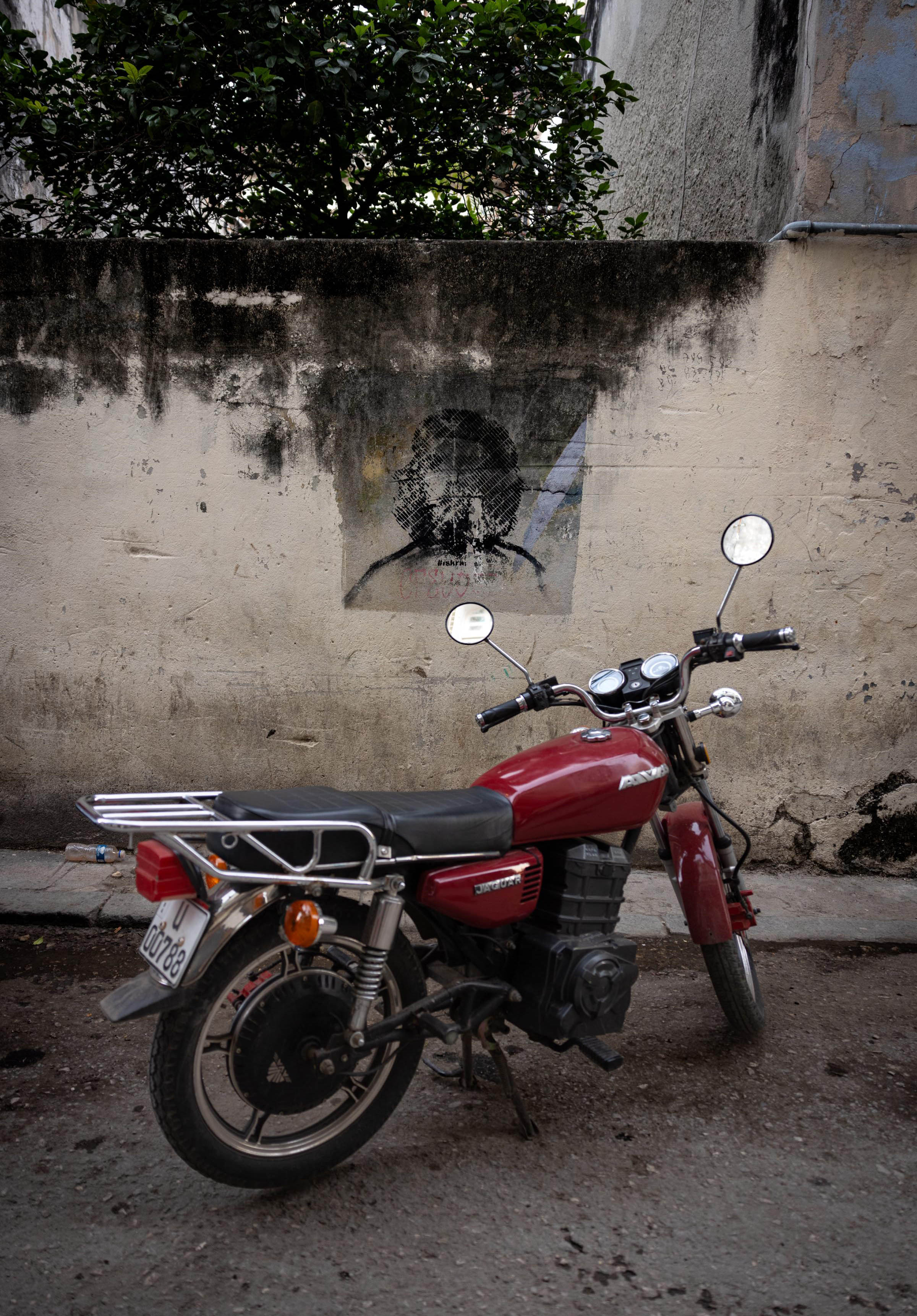 AVA Jaguar motorcycle parked in front of some Che Guevara street art. - Havana, Cuba