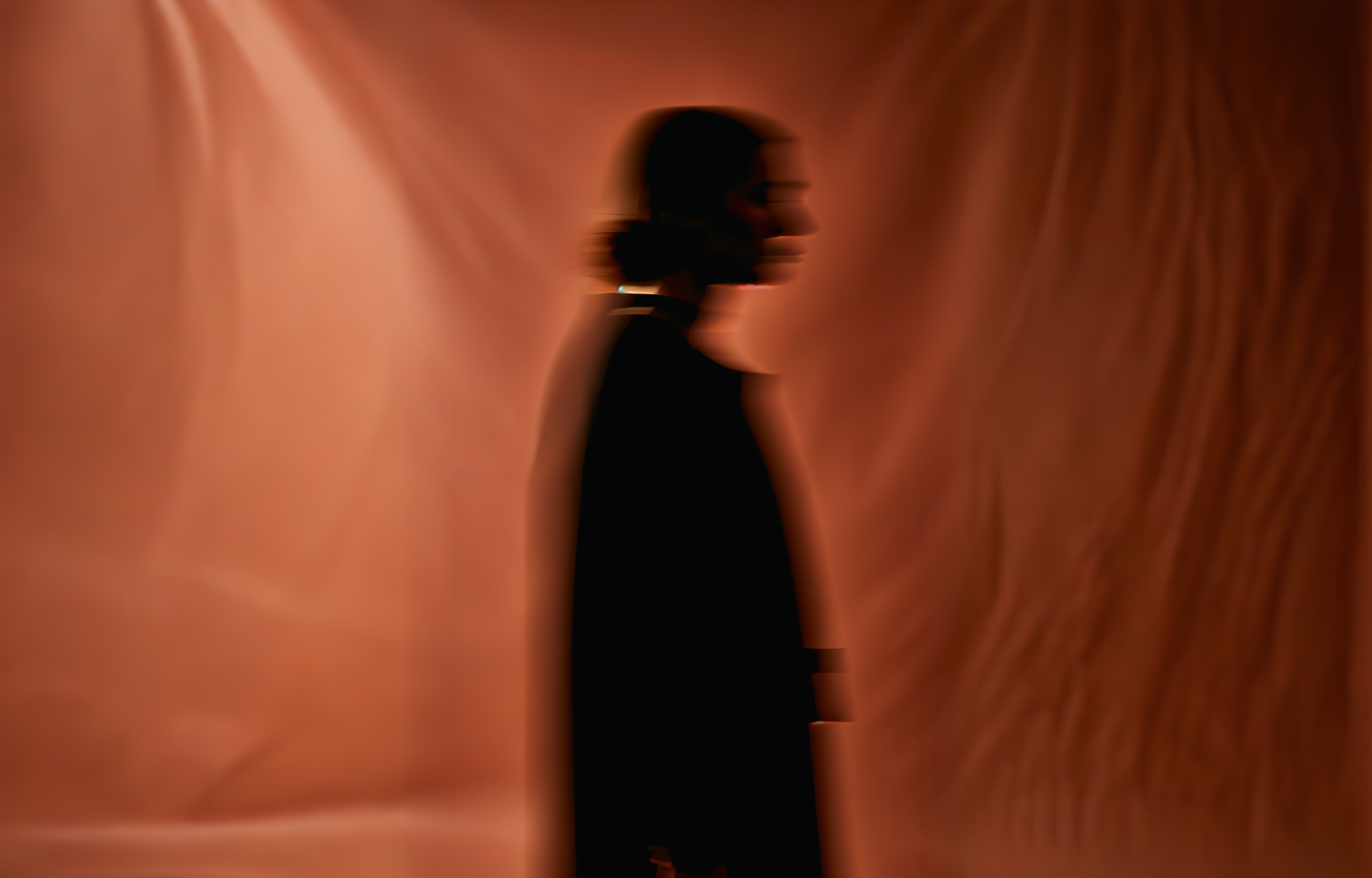 Silhouette of a woman against a dark brown silk background