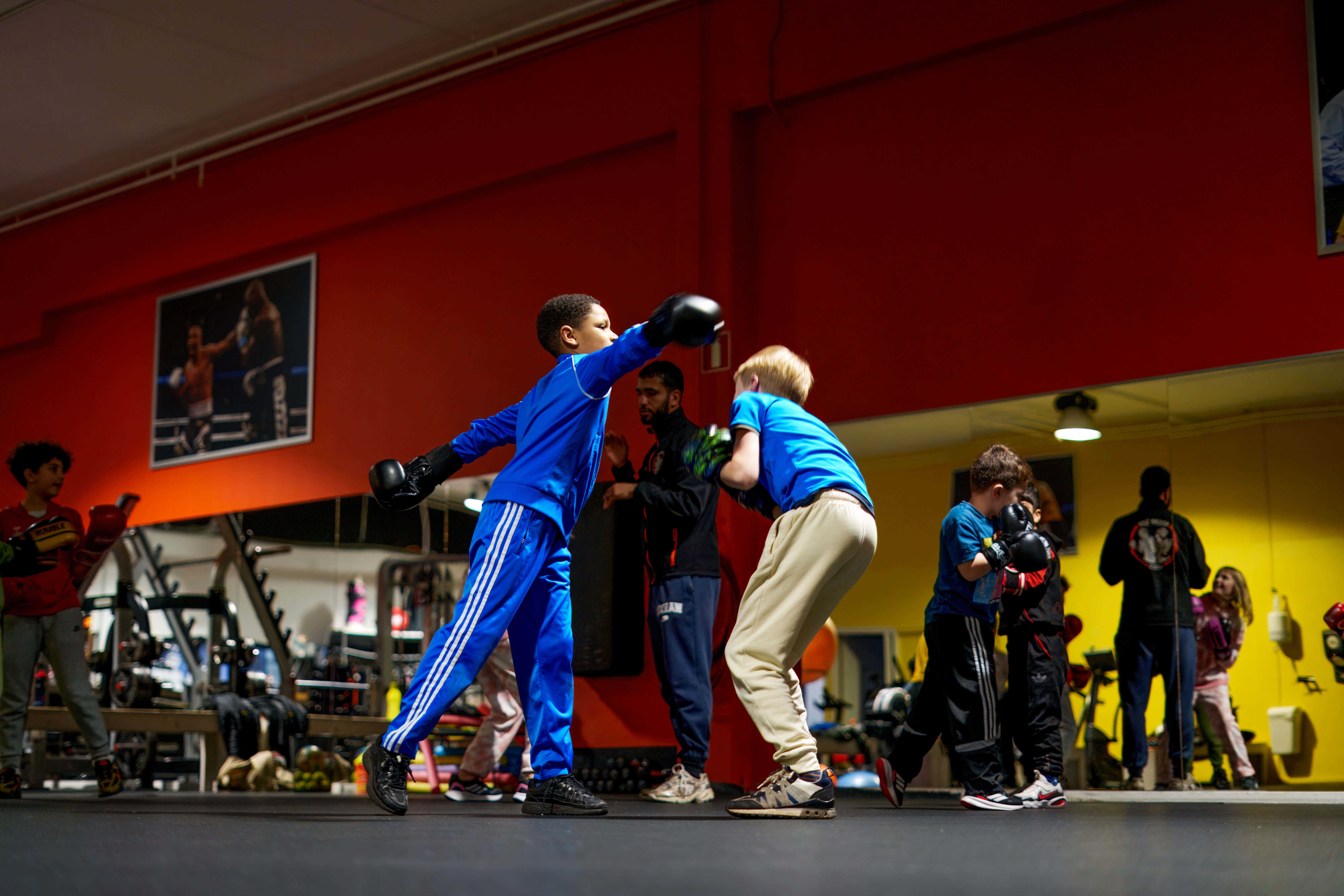 Kinderen trainen met bokshandschoenen in de zaal met rode muren