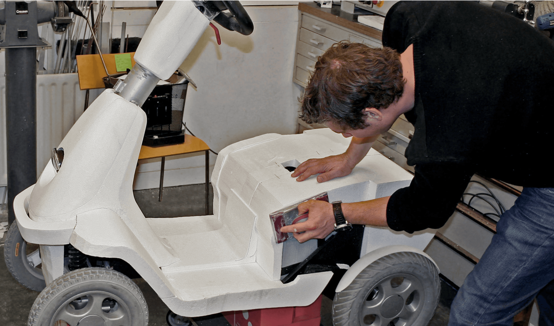 Image of a person creating a 1:1 styrofoam mock-up of a mobility scooter