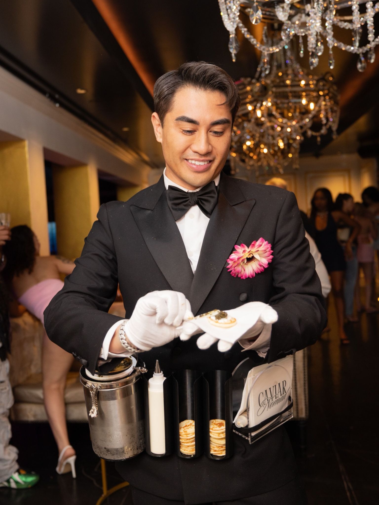 The Caviar Nomad host serving caviar on blinis at a luxury event.
