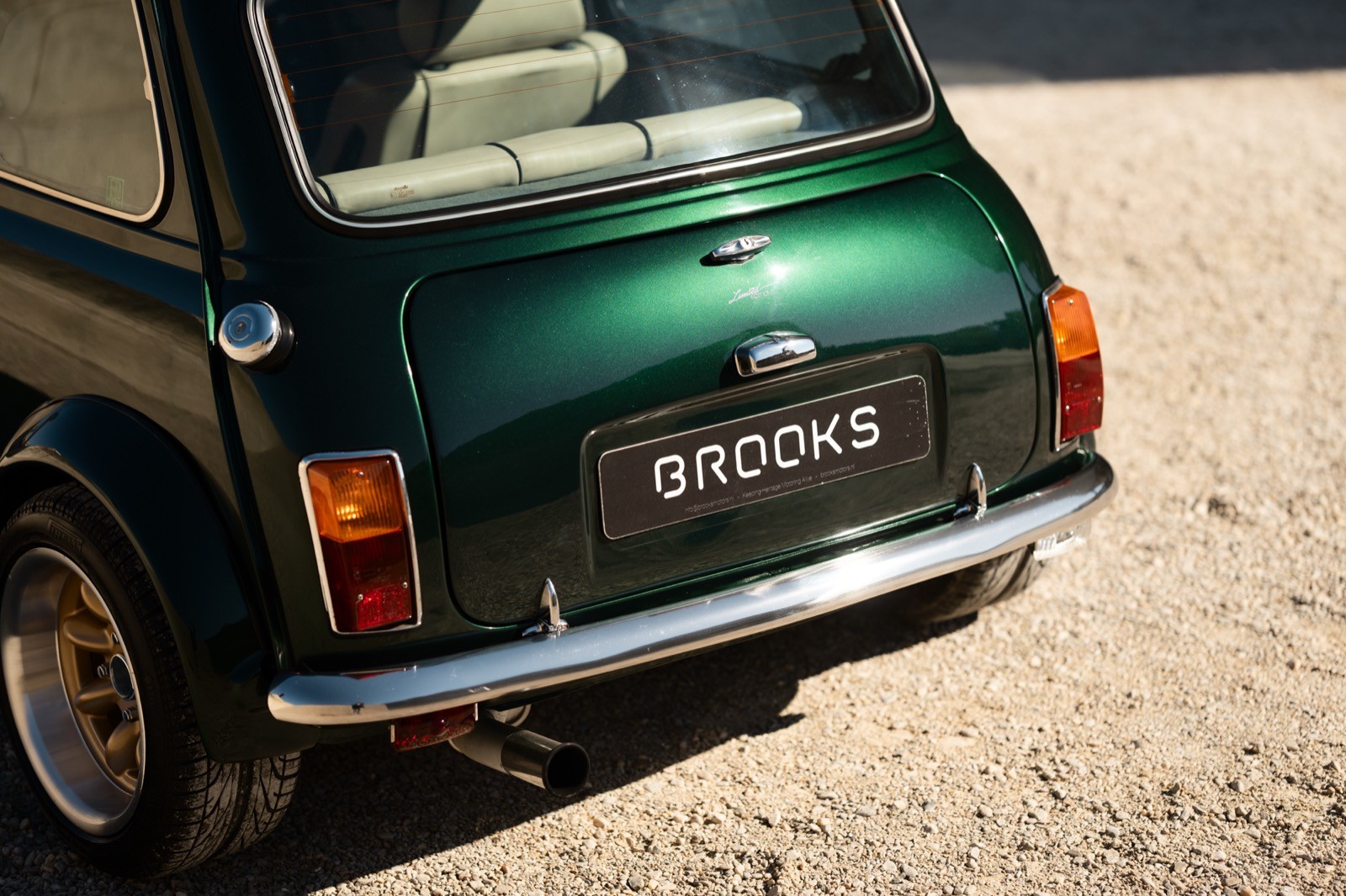 A small, green and black vehicle parked on a sandy surface, with a warm sunset lighting the scene.