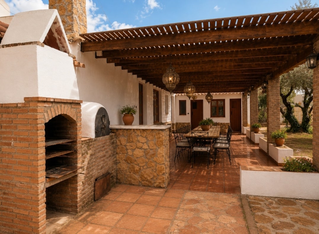 Cocina exterior y barbacoa de obra con horno de leña junto al porche