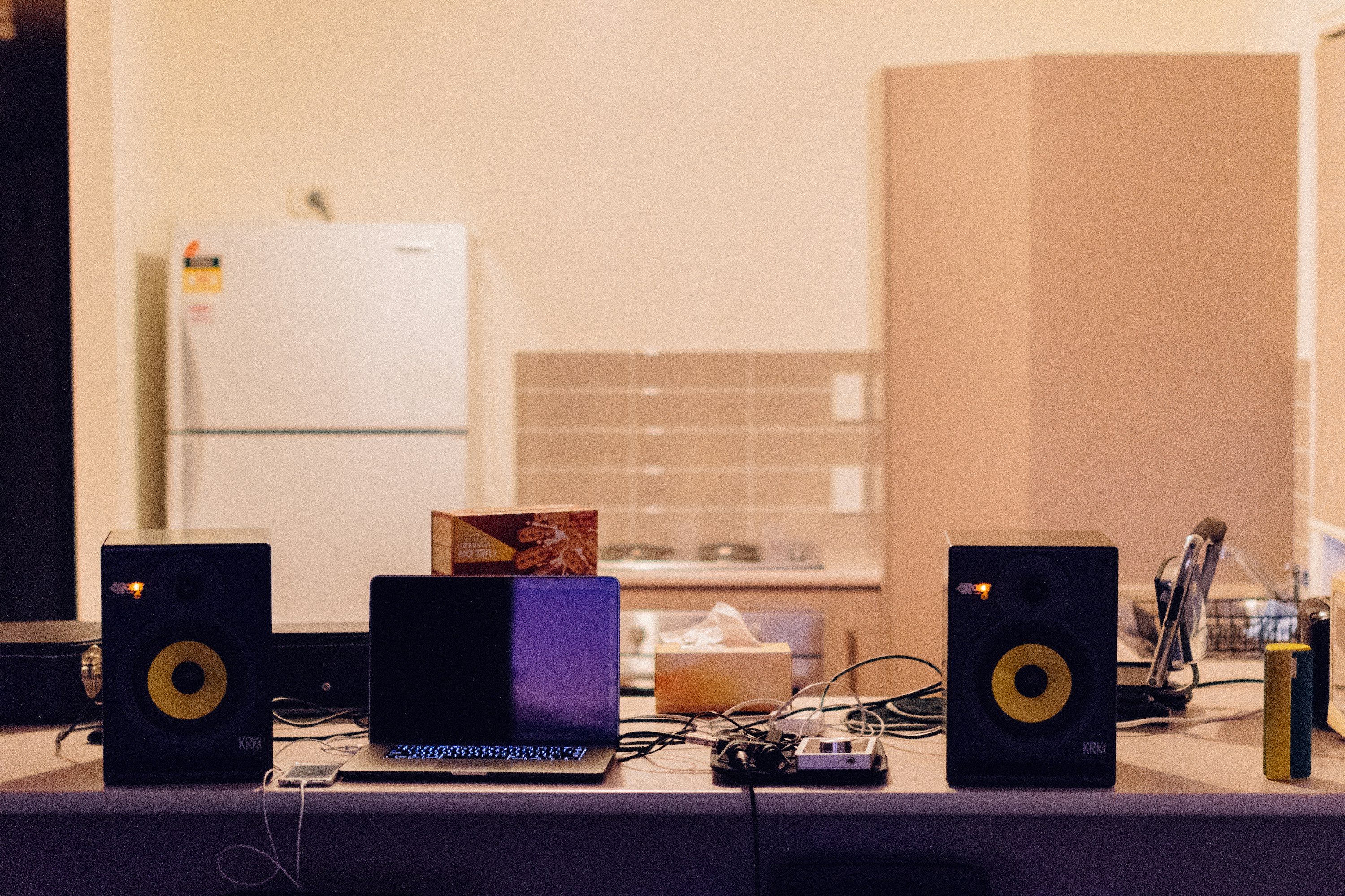 laptop on table next to two speakers in a music studio
