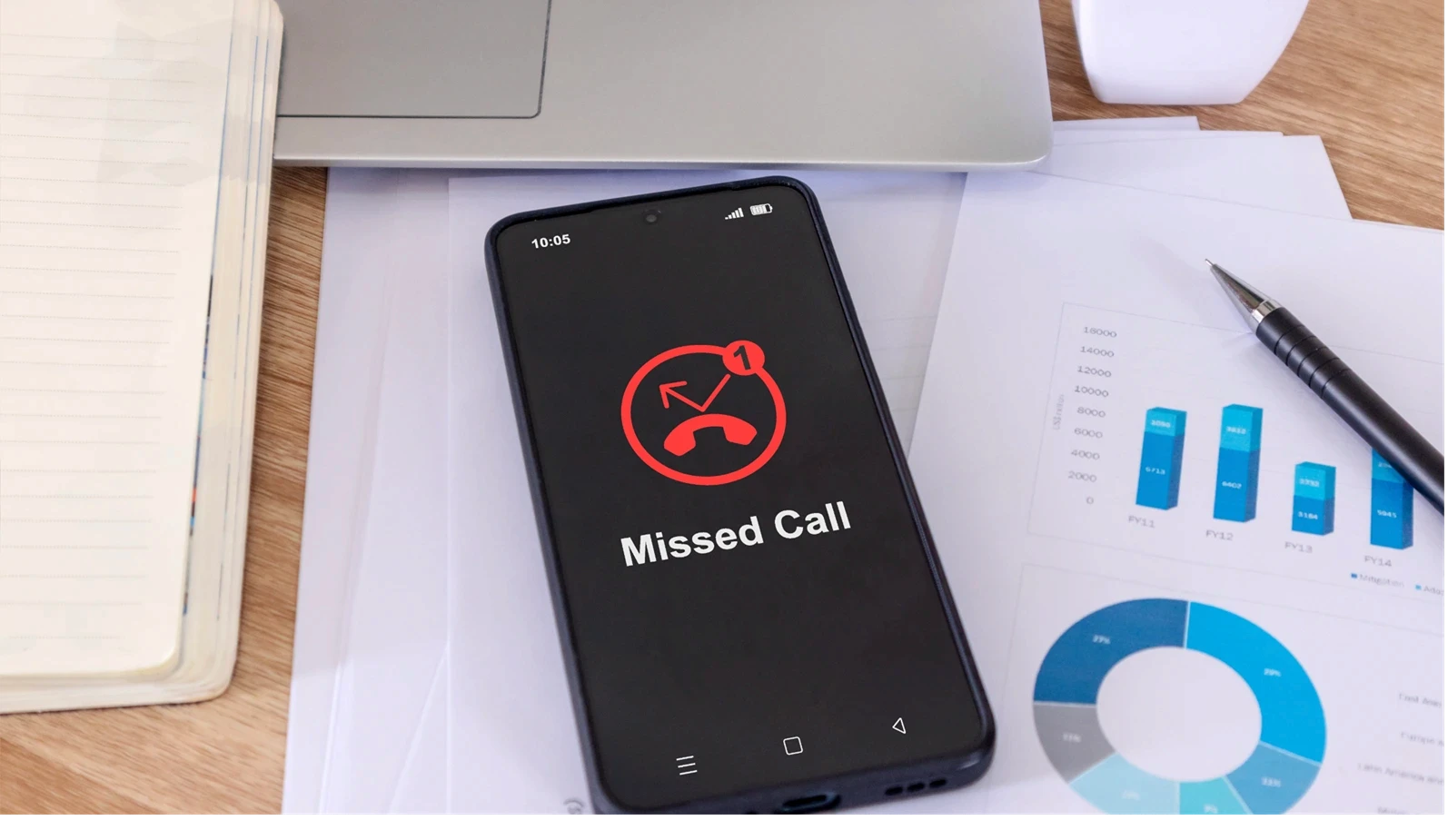 A mobile phone on a desk with a missed call notification on the phone screen