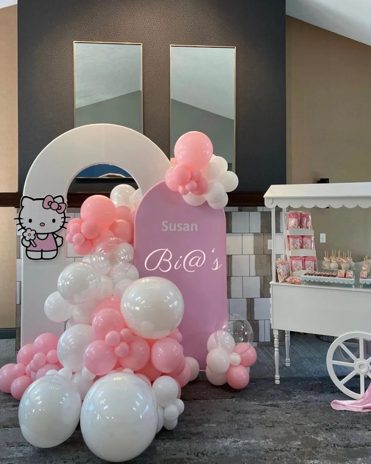 Pink and white balloon backdrop featuring a Hello Kitty theme, styled for a soft and elegant look with a custom name sign. Ideal for baby showers or young children’s birthday parties. Susa’s Sweets & Balloons.