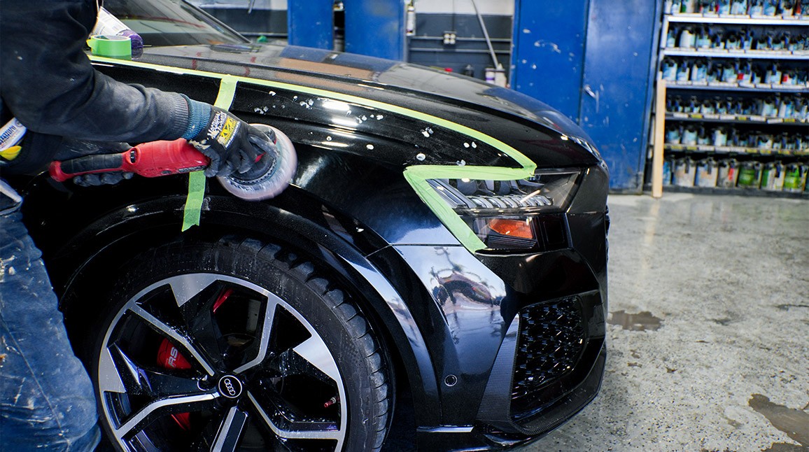 Auto Body Unlimited technician performing paint finishing on a vehicle during repair.