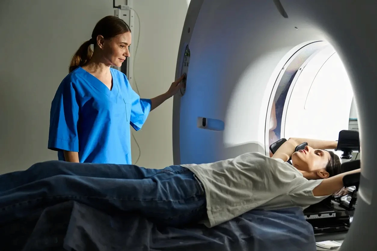 Radiology technologist operating CT imaging consoles alongside a Tether Supervision virtual contrast supervision unit, providing real-time radiologist oversight for safe, compliant contrast administration in outpatient imaging centers.