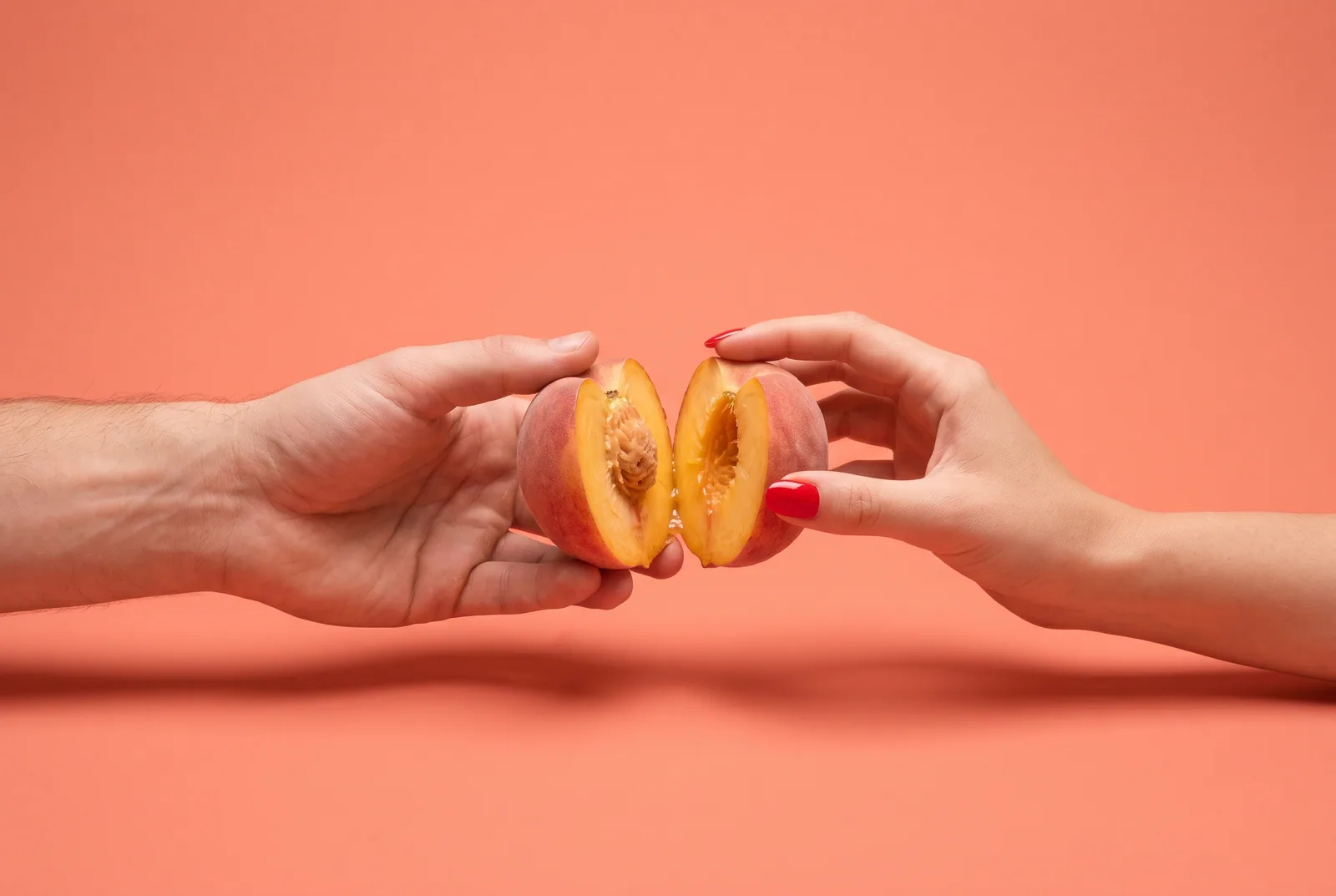 Row of bananas standing like dominoes on a coral backdrop with one tipping over and a cropped hand catching it, a metaphor for handling a relapse while rebuilding trust after porn addiction
