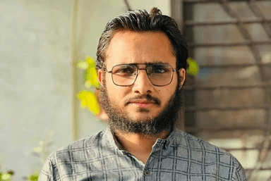 A man with glasses standing in front of a building