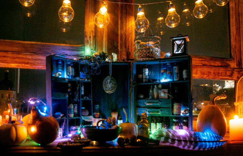 A mystical, dimly lit room adorned with various potion bottles, glowing lights, pumpkins, and candles, evoking a magical and enchanting atmosphere.