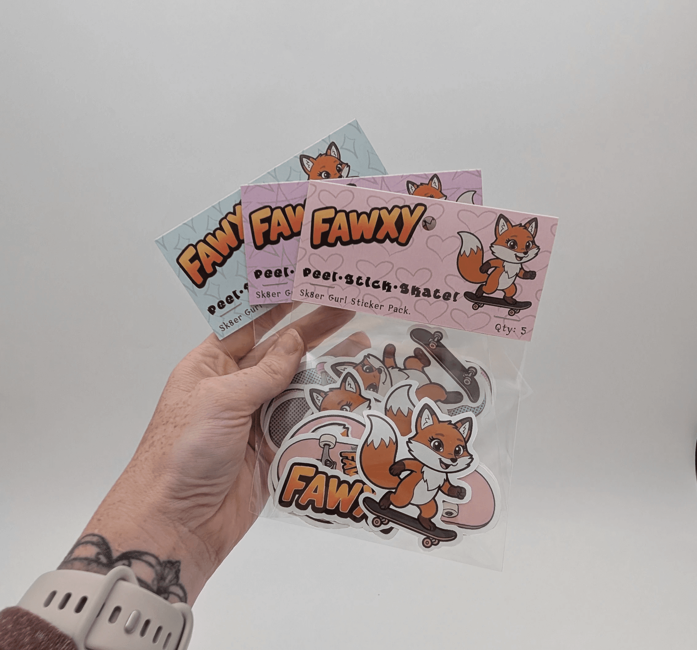 a hand holding 3 sticker packages