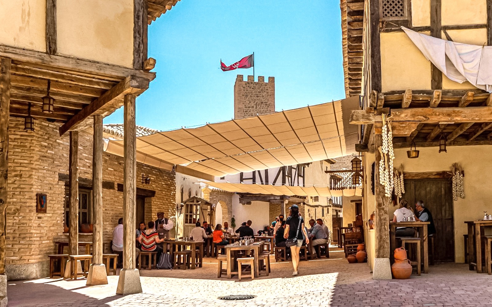 Visitors dining in a medieval village setting at Puy du Fou Park.