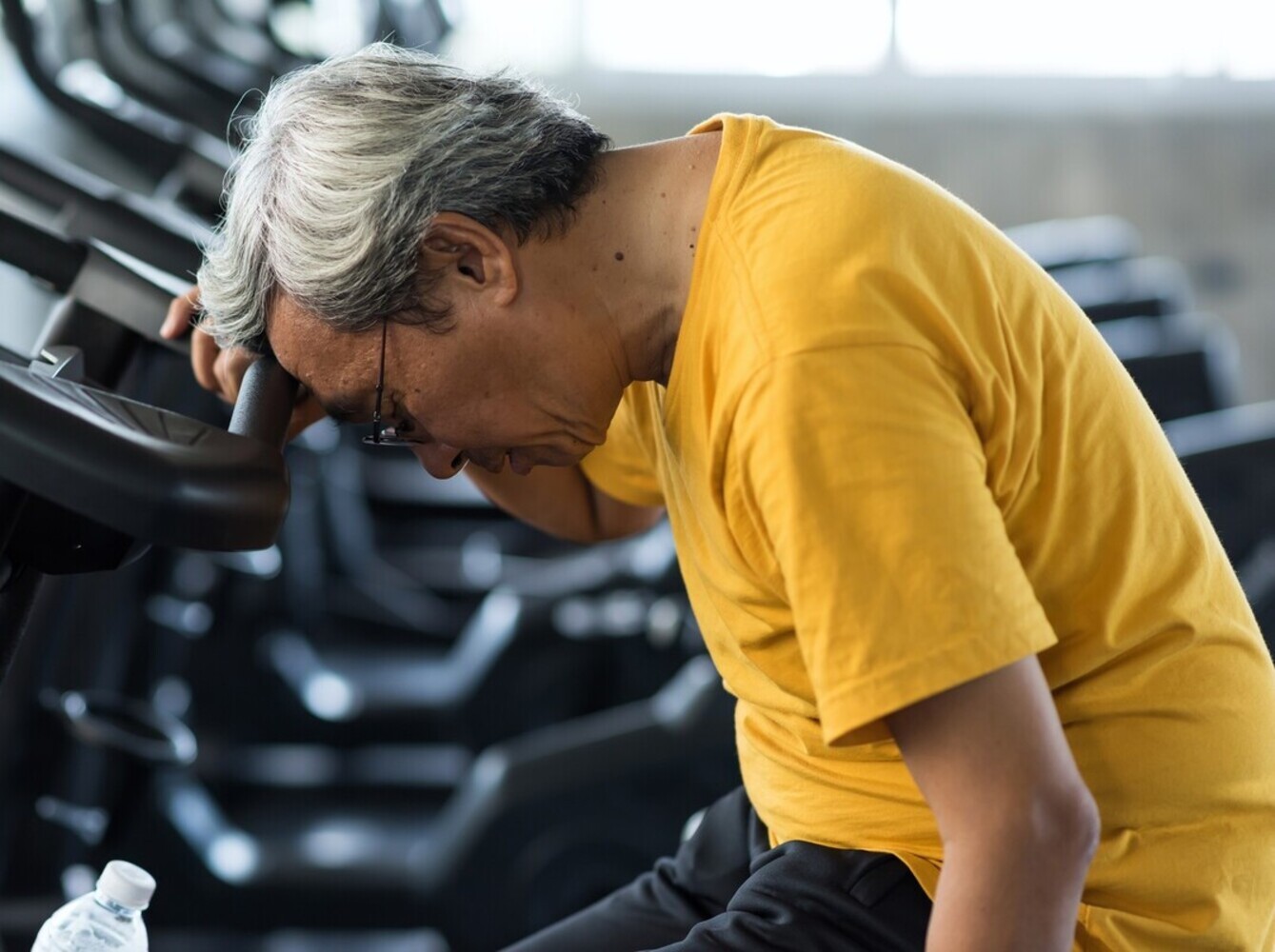 older man feeling dizzy at the gym after overdoing how much StairMaster to lose weight