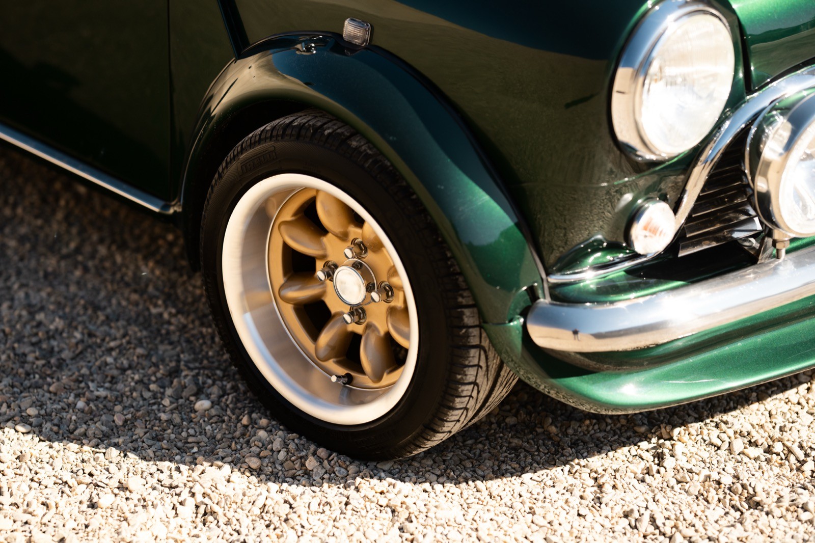 A small, green and black vehicle parked on a sandy surface, with a warm sunset lighting the scene.