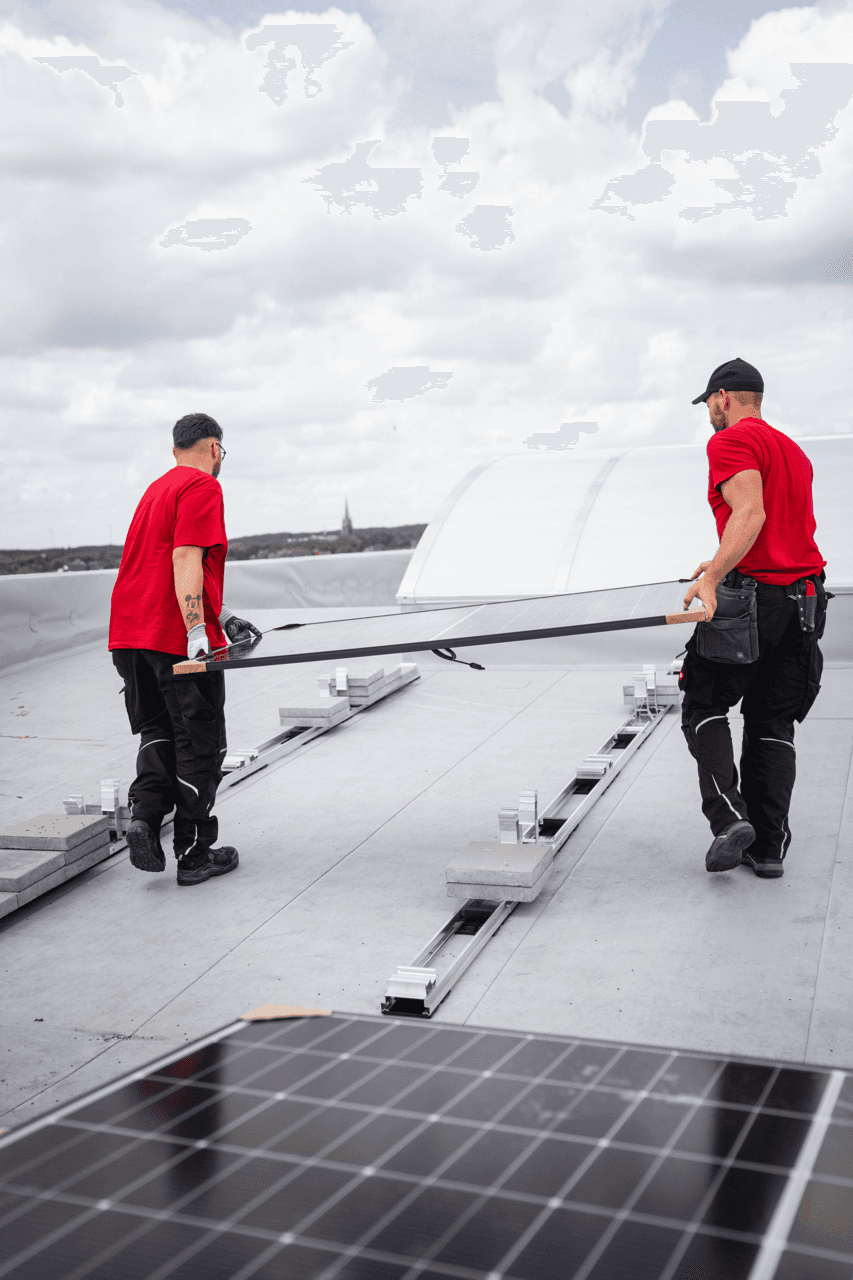 Sprick Monteure tragen Solarmodul lehnend am Auto lächeln sich an