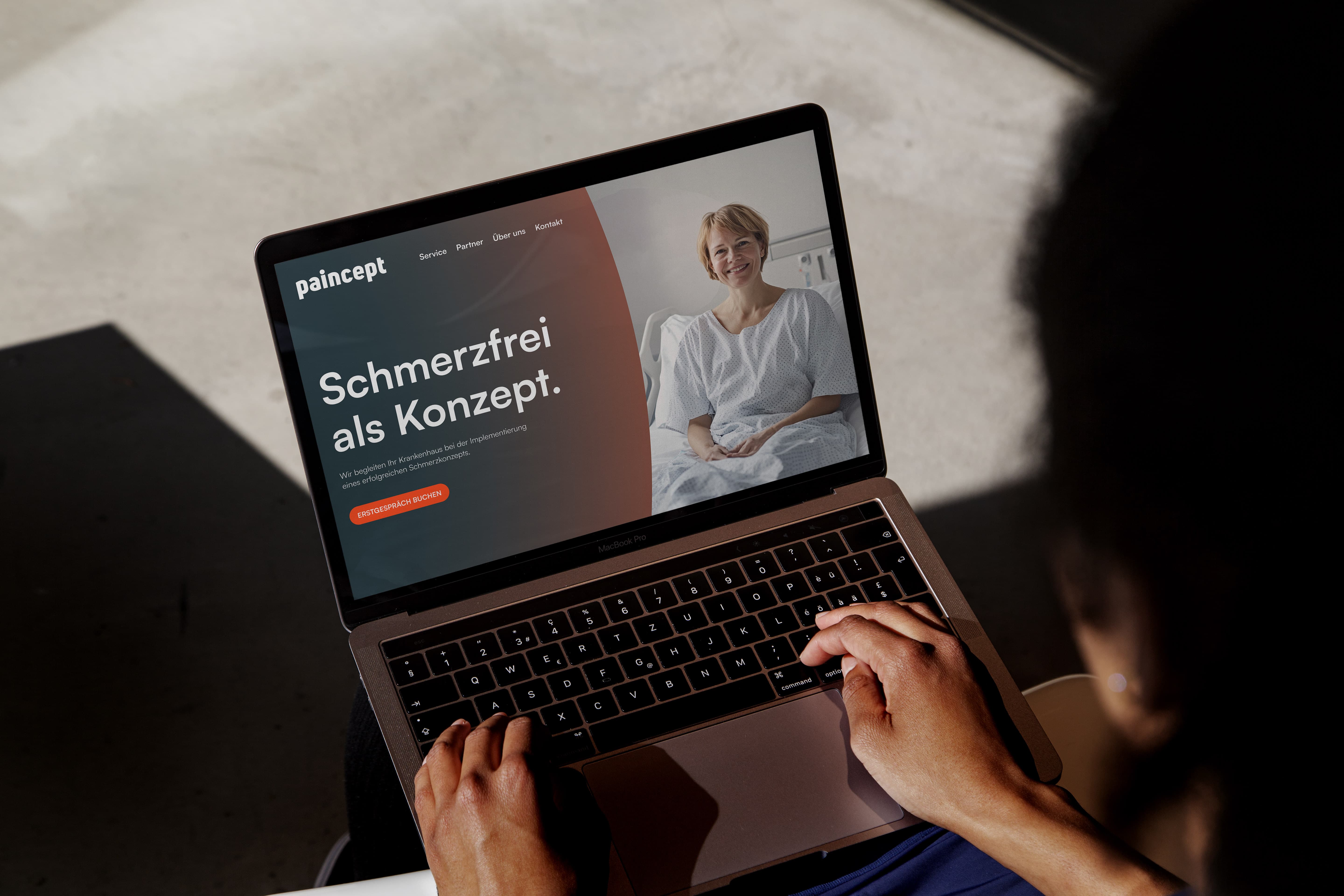 Ein Foto von der Webseite der Markenentwicklung von paincept. Zu sehen ist die Landing page, die das Key Visual und das AI-generierte Foto einer glücklichen Frau im Krankenbett zeigt. Der Slogan ist "Schmerzfrei als Konzept"