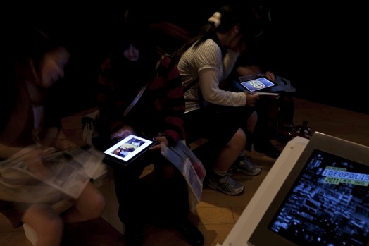 people in a dark room looking at iPads