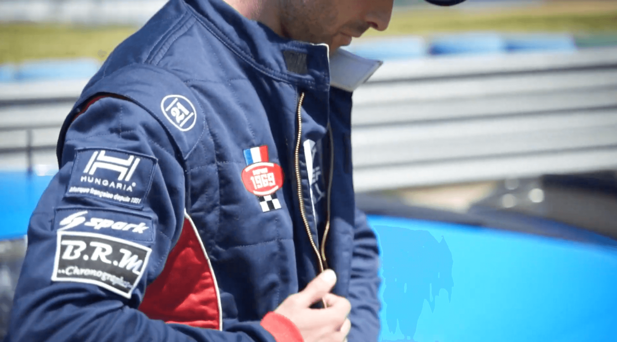 Person in a dark shirton a phone call, seated at a desk with papers, exudes a thoughtful, focused demeanor. Background shows dark horizontal blinds.