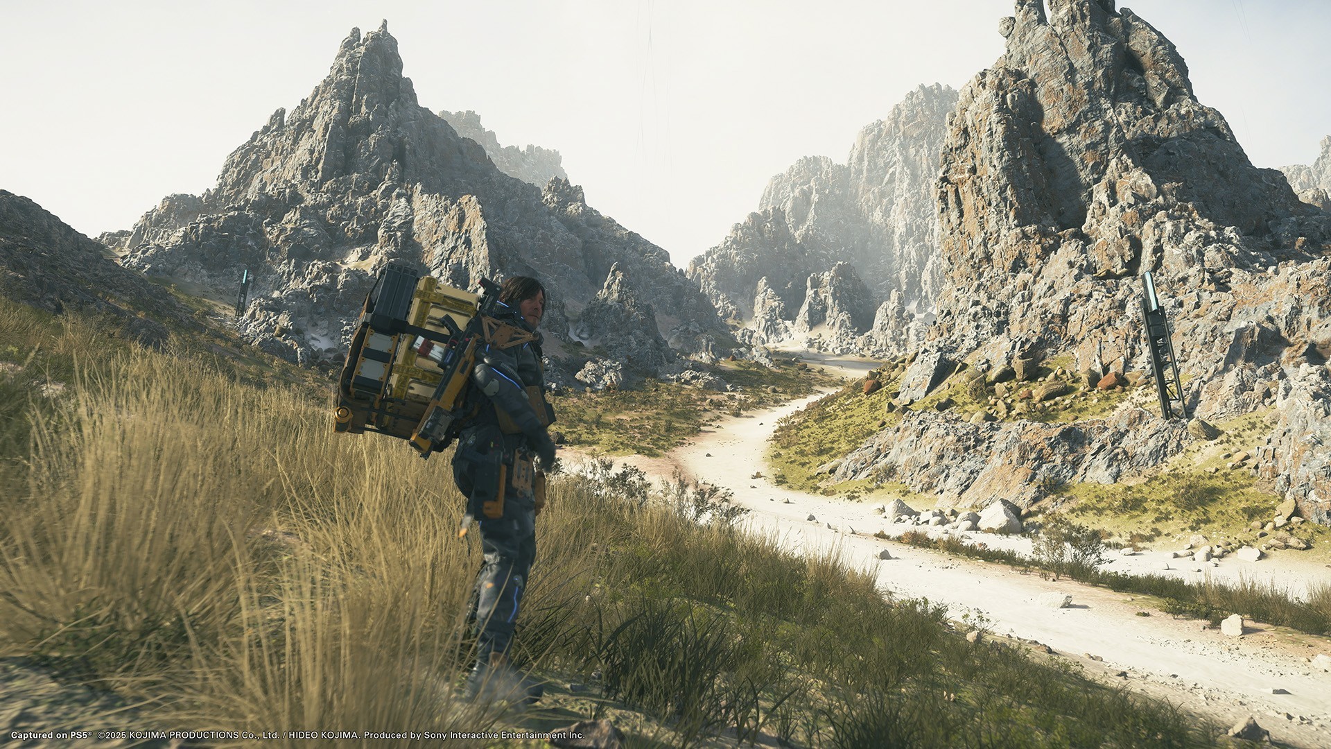 Death Stranding 2 exploration paysage montagneux vaste monde ouvert Sam Bridges transport équipement post-apocalyptique PC