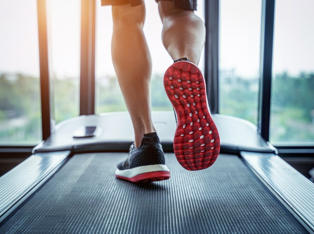 closeup of a person using a treadmill instead of a bike for weight loss at the gym