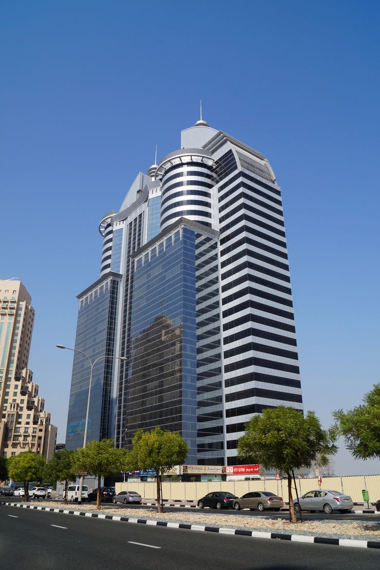 Low angle view of the modern glass facade of SIT Tower, a prime commercial property in Dubai Silicon Oasis.