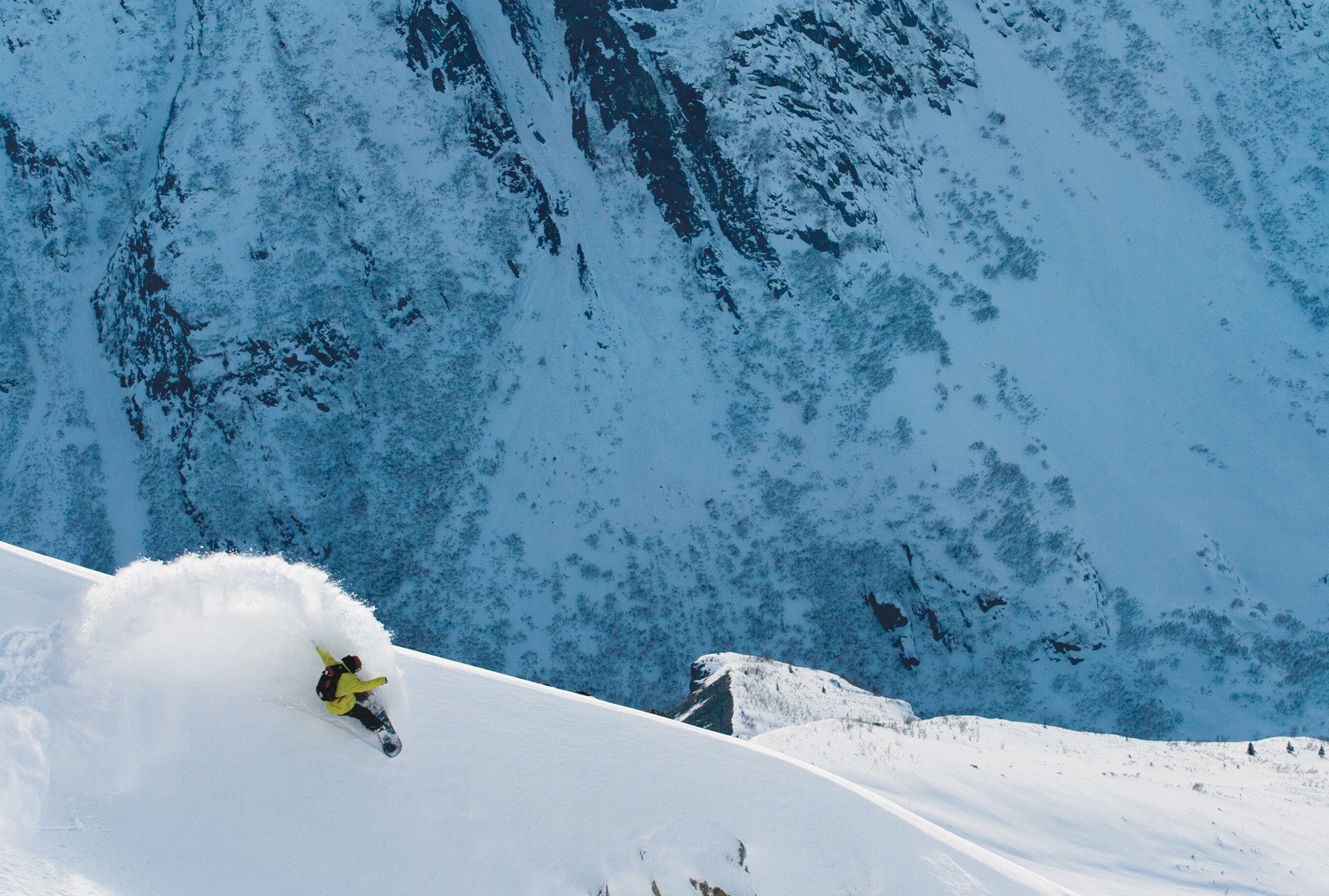 Flow snowboarder carving powder on a steep alpine ridge