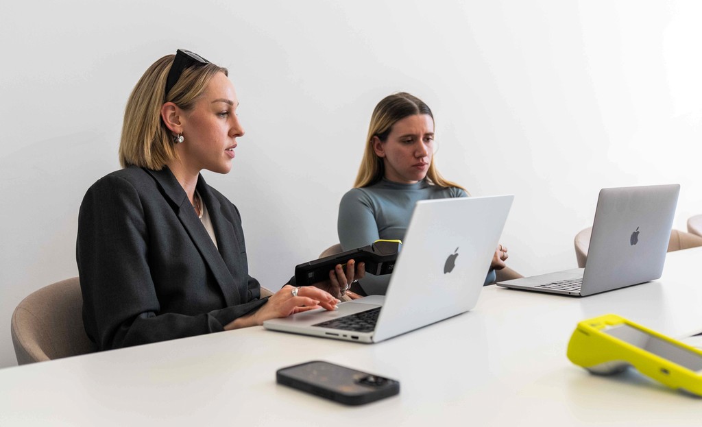 two women business owners hold Teya card machines to perform accounting tasks in a dedicated software
