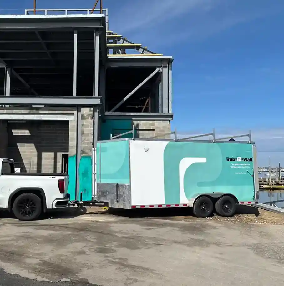 A photo of a waterproofing work truck hauling a Rub-R-Wall® trailer to a job site on an ocean harbor
