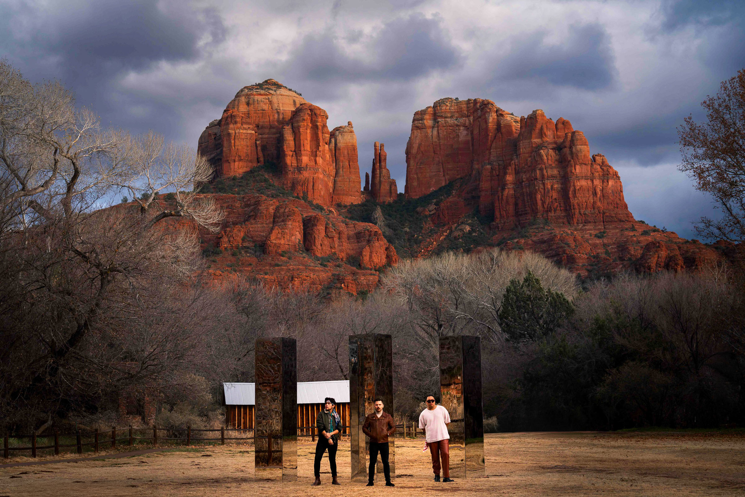 The band ARIZONA standing in front of three mirror monoliths with Cathedral Rock in the background