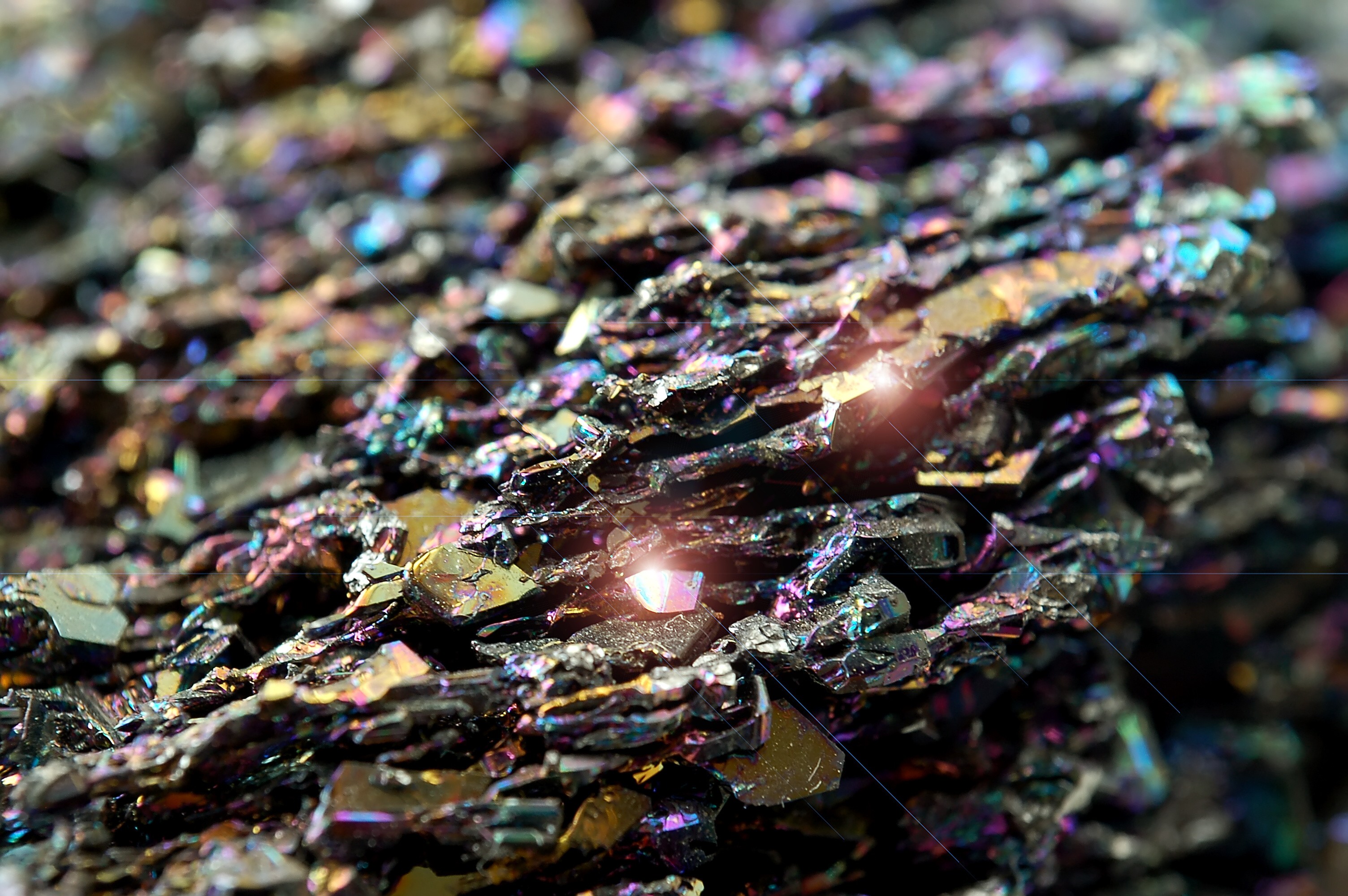 Extreme close-up of iridescent, multi-coloured mineral crystals catching the light