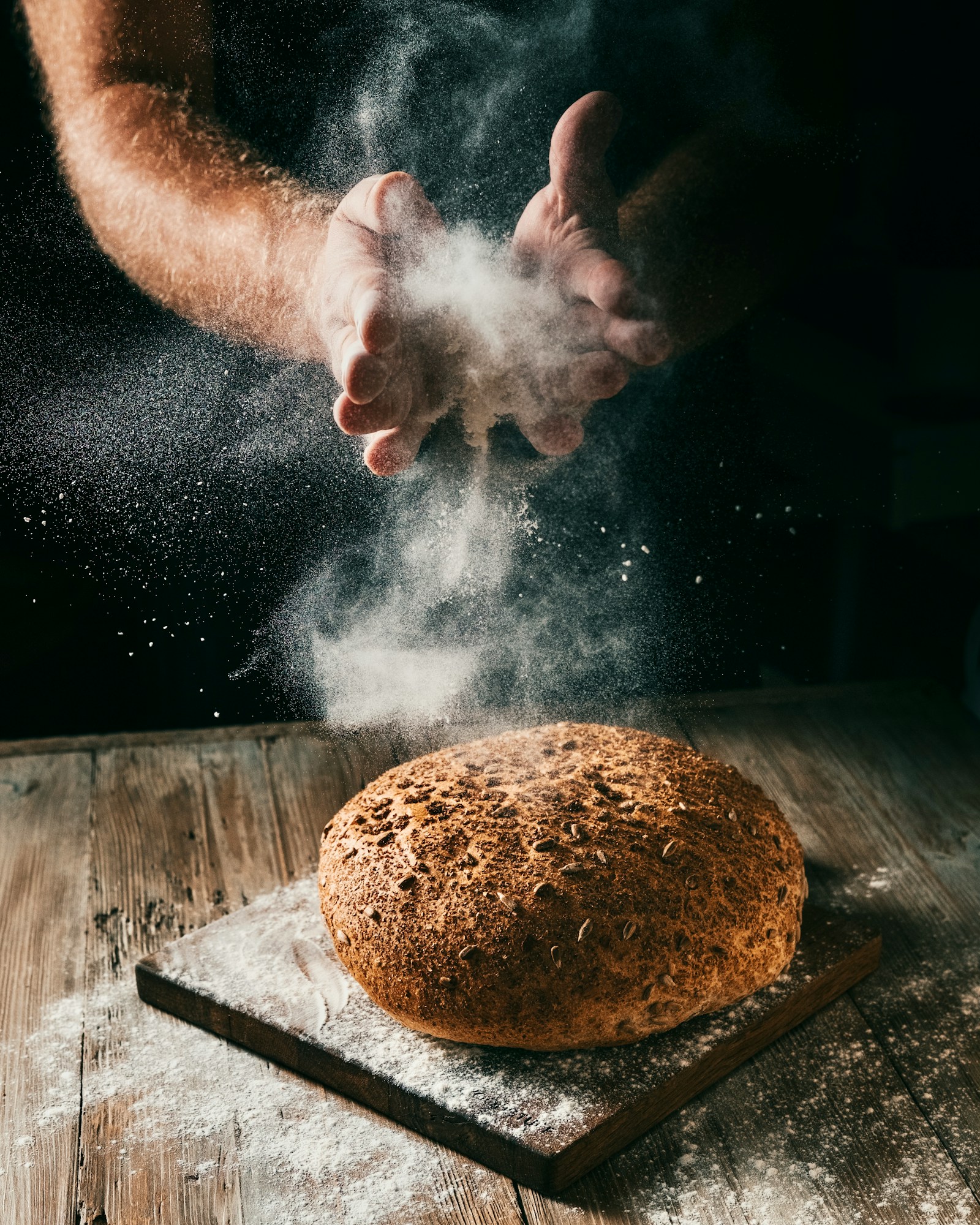 Baker dusting flour over a round loaf