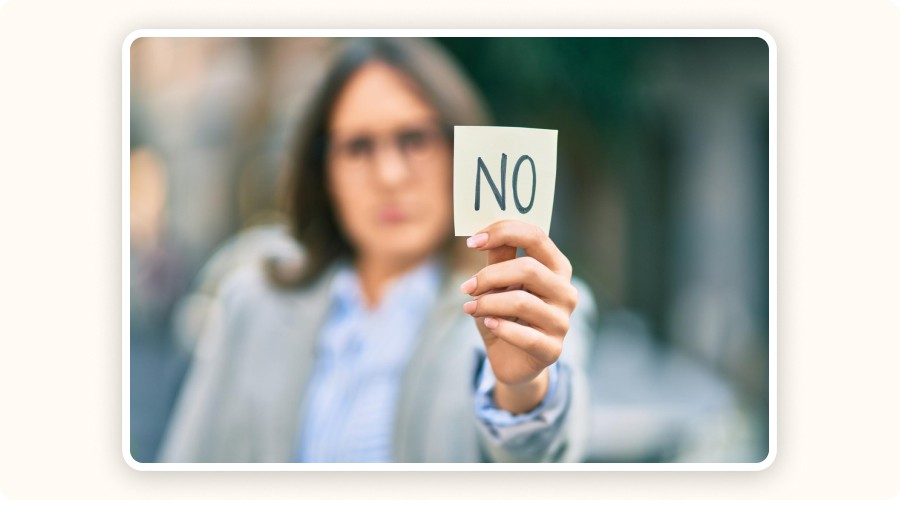 Femme tenant un panneau “NO” avec expression sérieuse.&nbsp;