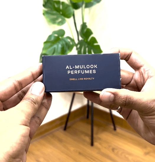 Hands holding Al-Mulook business card with minimal logo and typography.