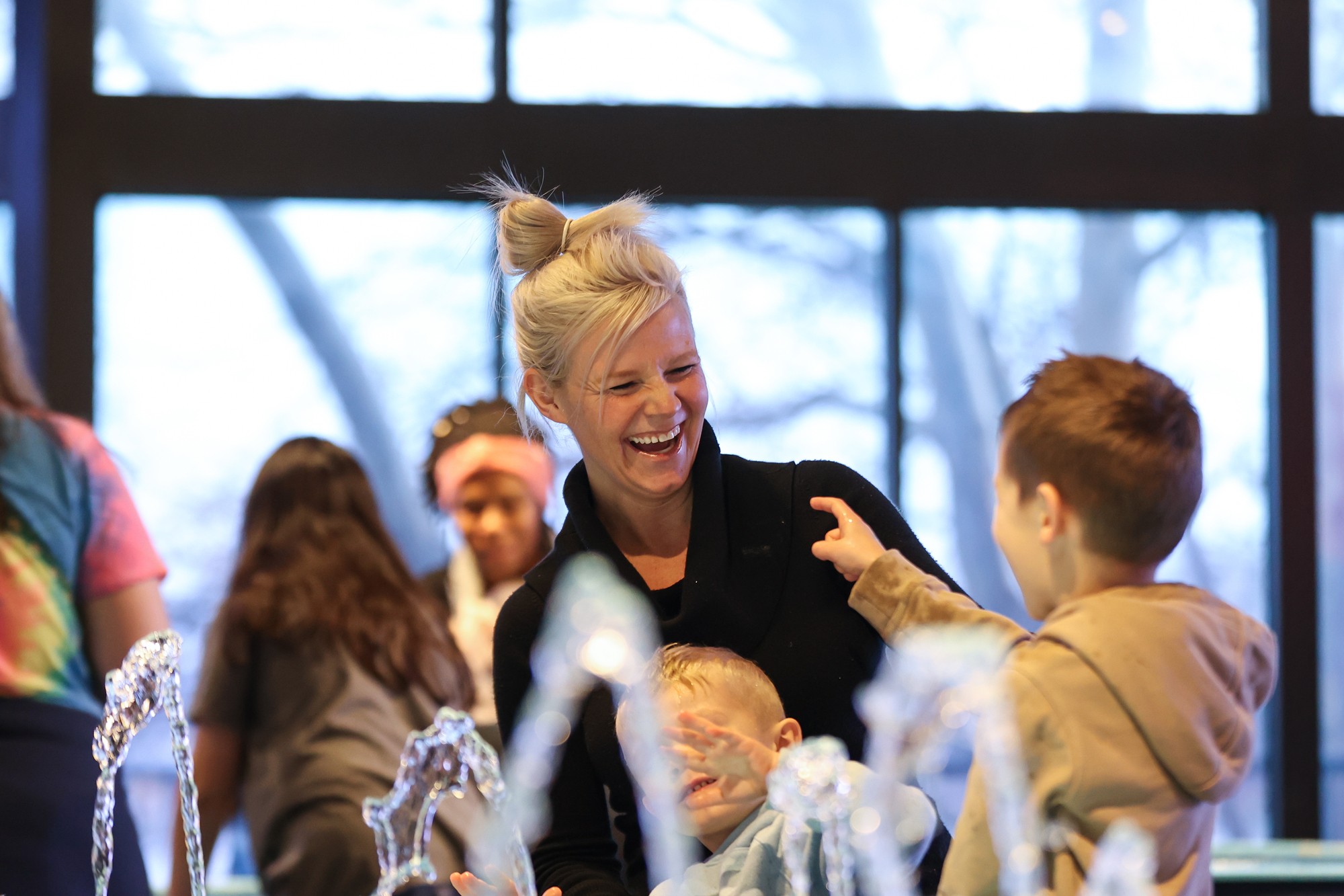 A mom and young boy laugh as they play at the water tables in the Water Works exhibit.