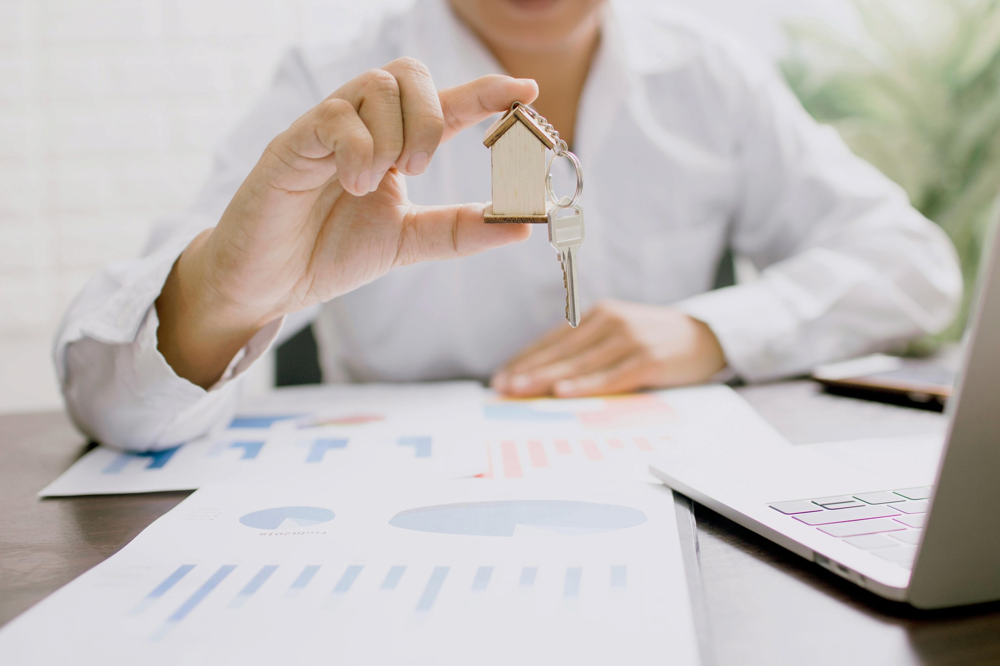 women holding a model of a house as she looks through real estate marketing data for their seo campaign