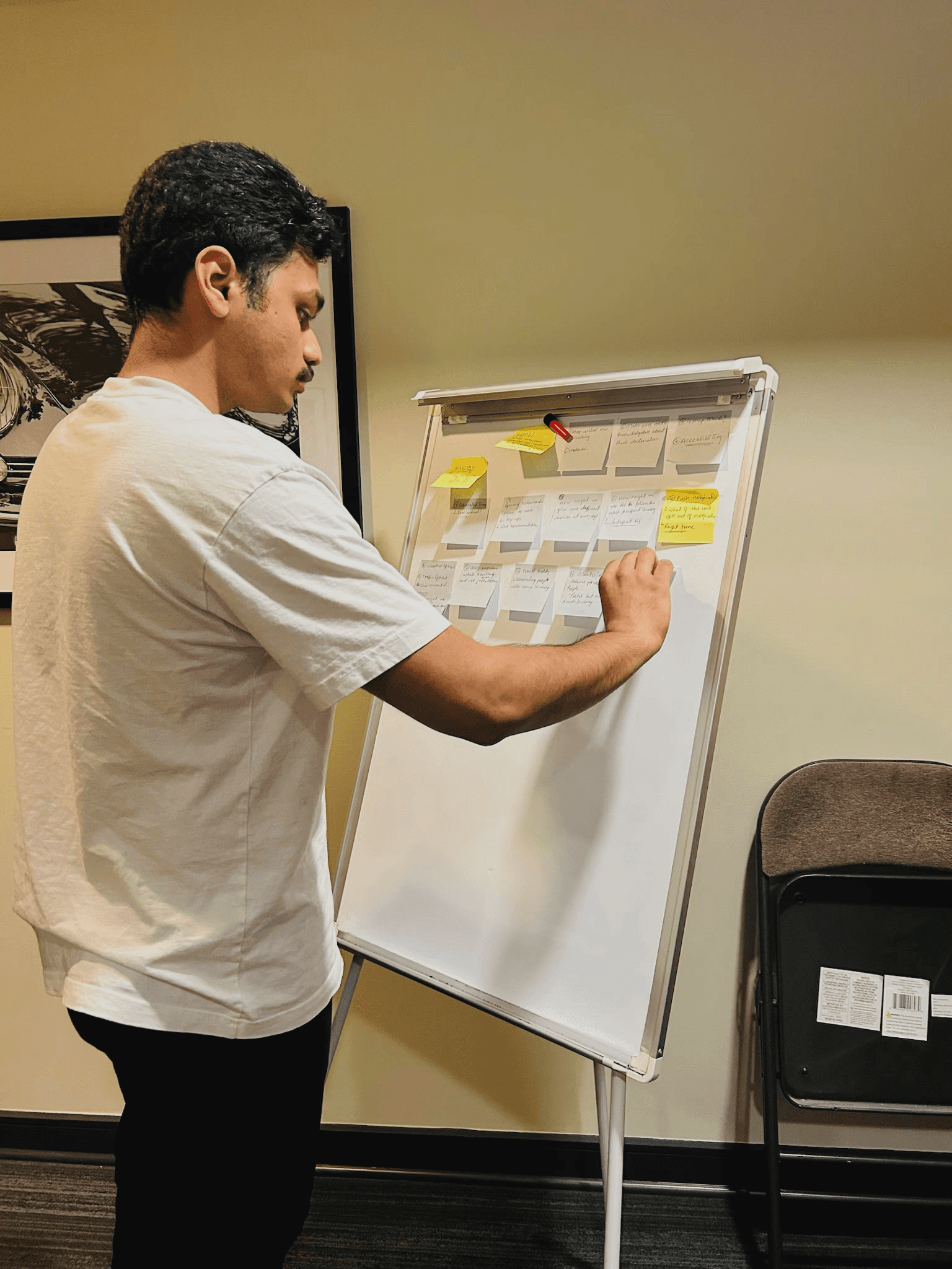 A man putting sticky notes on a white board