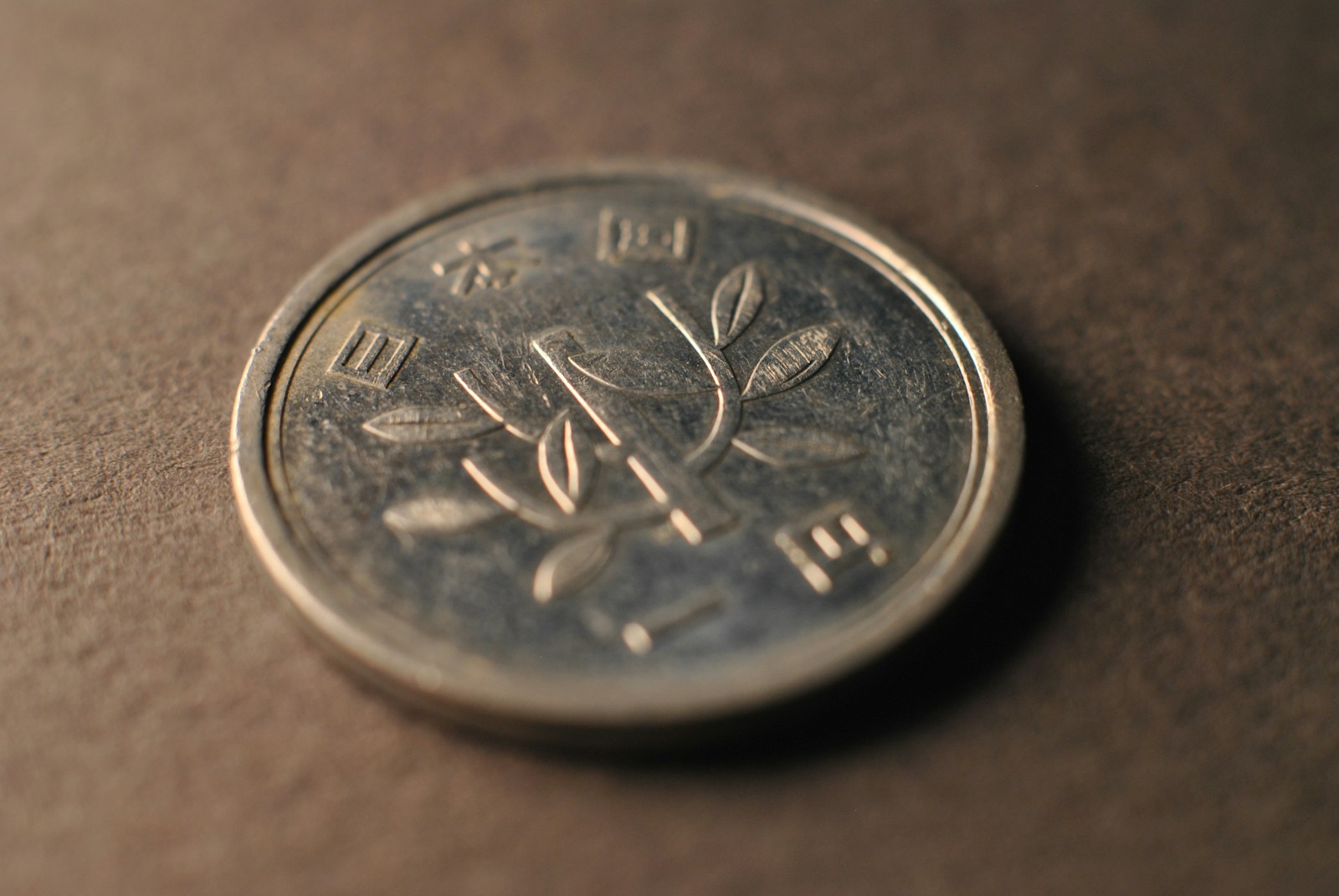 Close-up of a Japanese 100 yen coin showing its cherry blossom design