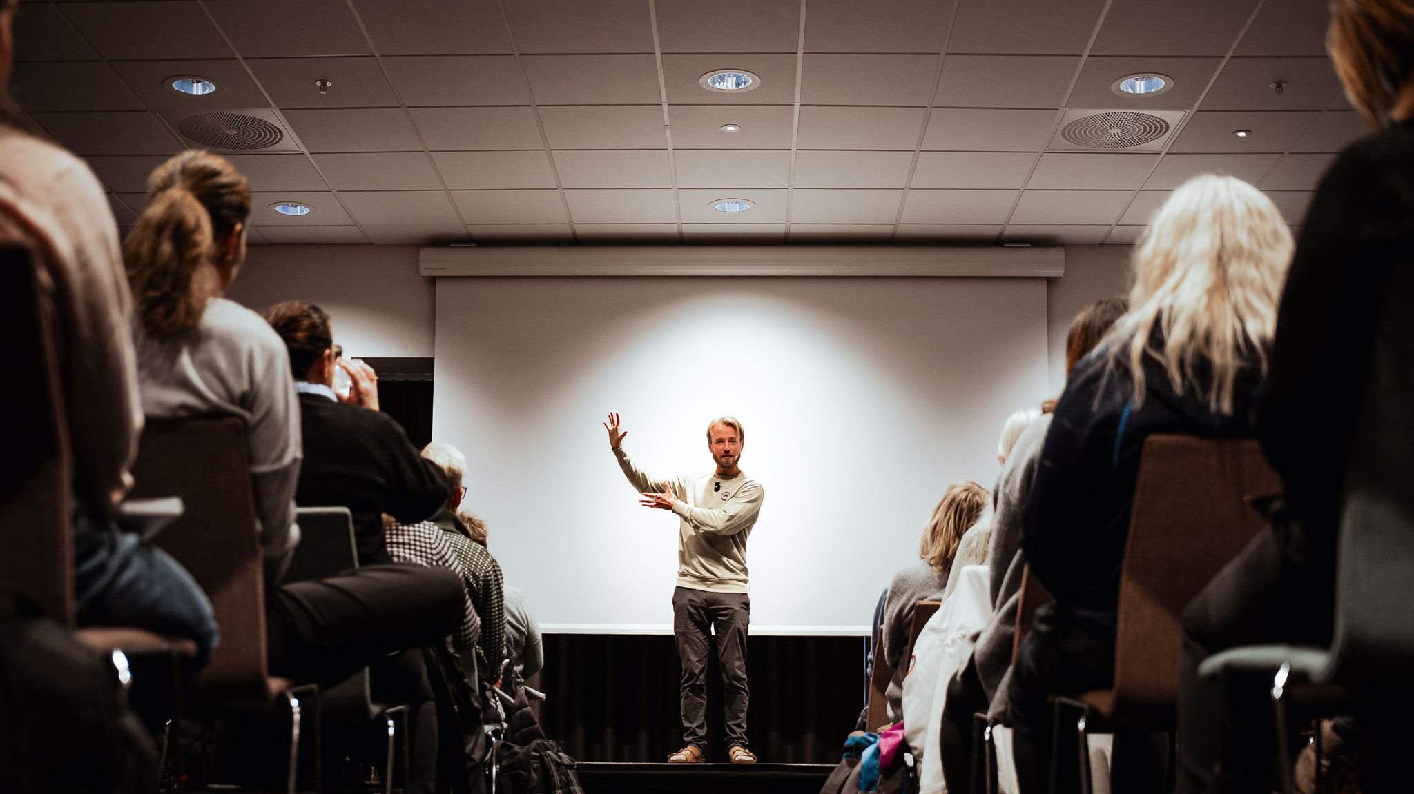 A young soccer goalkeeper in a neon green jersey holding a star-patterned ball with gloved hands.