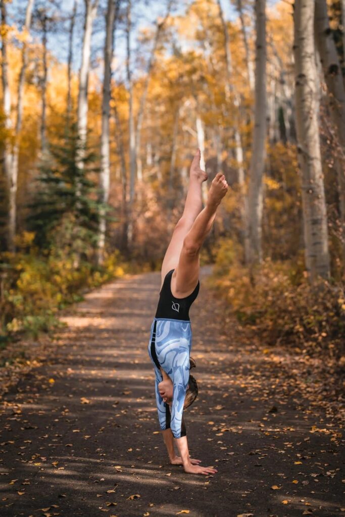 Person performing a handstand on a path through autumn aspens
