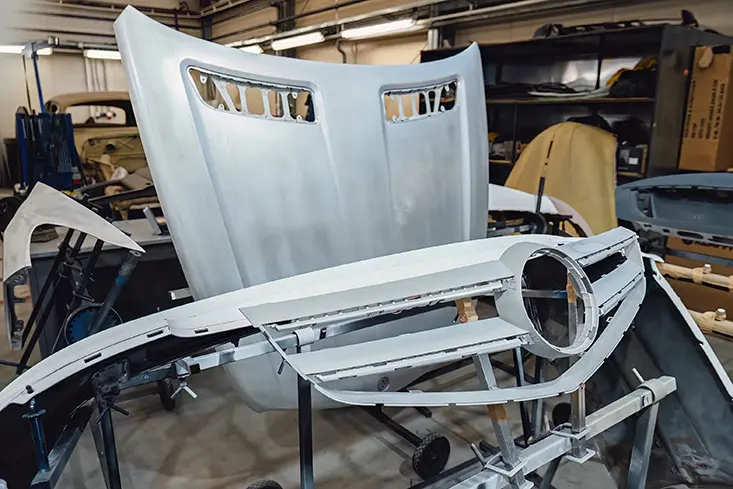 Disassembled vehicle body components staged for frame and structural repair inside an auto body facility.